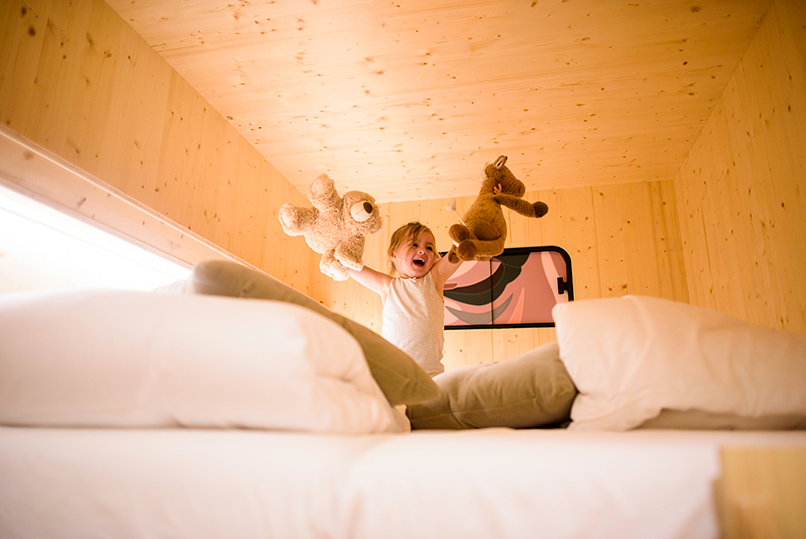 Klein meisje speelt op het bed in de privékamer van The Green Elephant Hostels