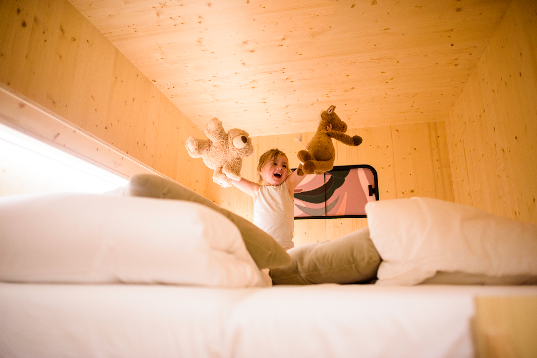 Klein meisje speelt op het bed in de privékamer van The Green Elephant Hostels