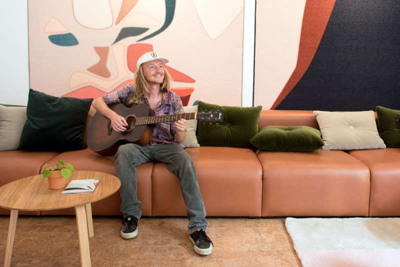 Persoon die gitaar speelt in de lobby van The Green Elephant Hostels